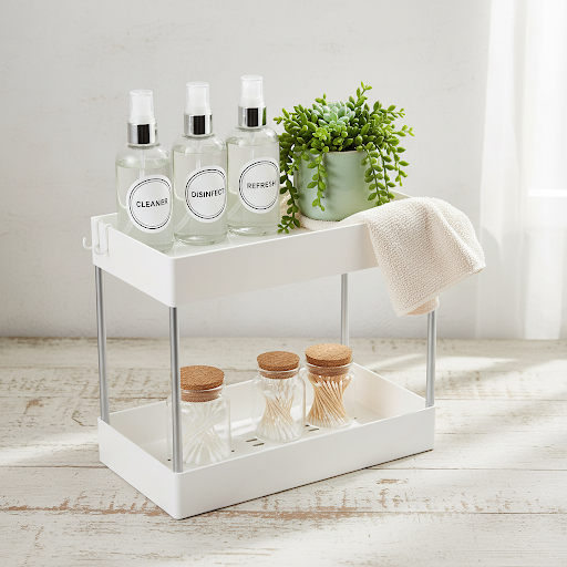 White two-tier storage organizer for bathroom and kitchen countertop storage with spray bottles and daily essentials